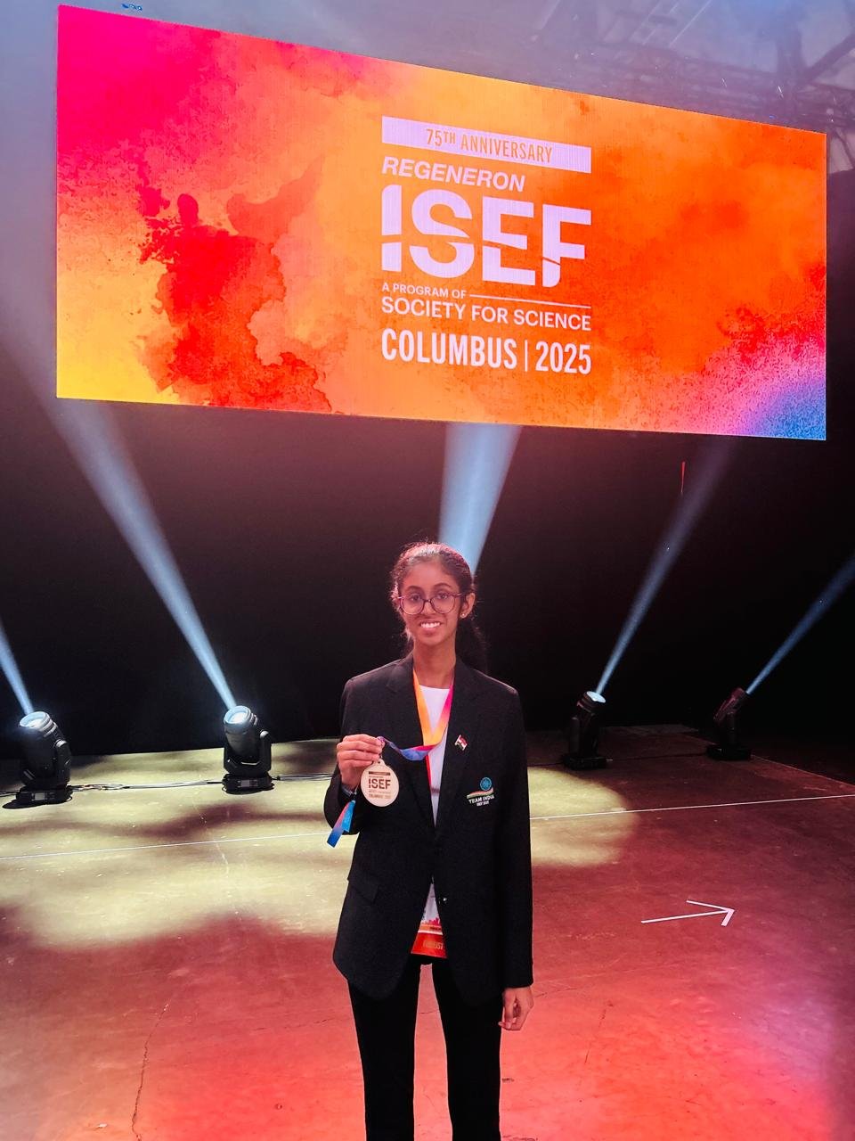 Ananya Ganapathy on the Regeneron ISEF awards stage, holding her medal, Columbus 2025